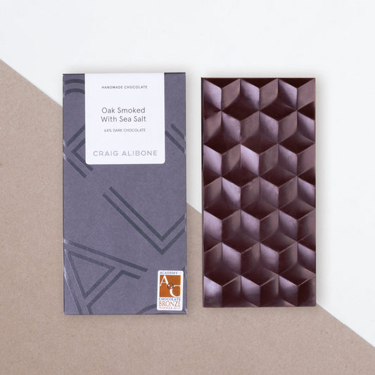 Photo of a chocolate bar packaging sized by side with the unpacked chocolate bar.  You can see the beautifully designed packaging and textured pattern on the chocolate bar. 